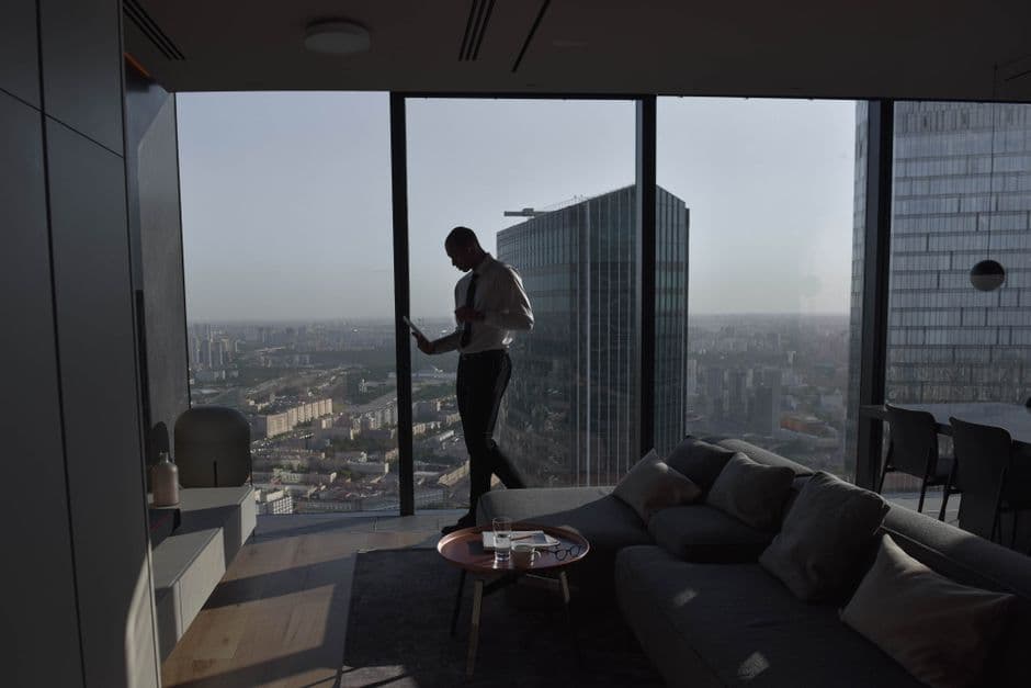 Silhouette of a businessman standing in a luxury apartment with a panoramic cityscape view.