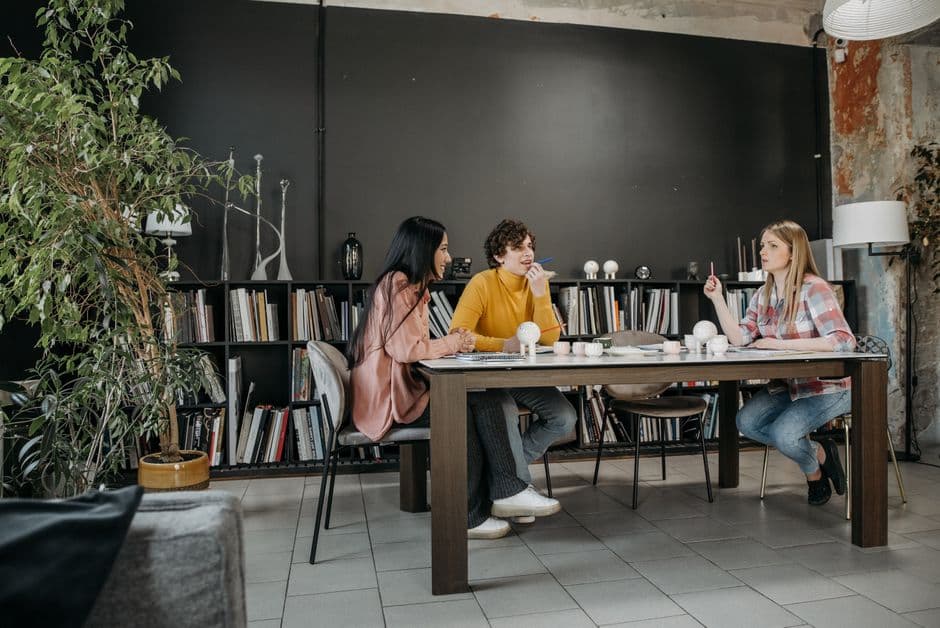 Three adults discuss ideas in a stylish office setting, fostering creativity and teamwork.
