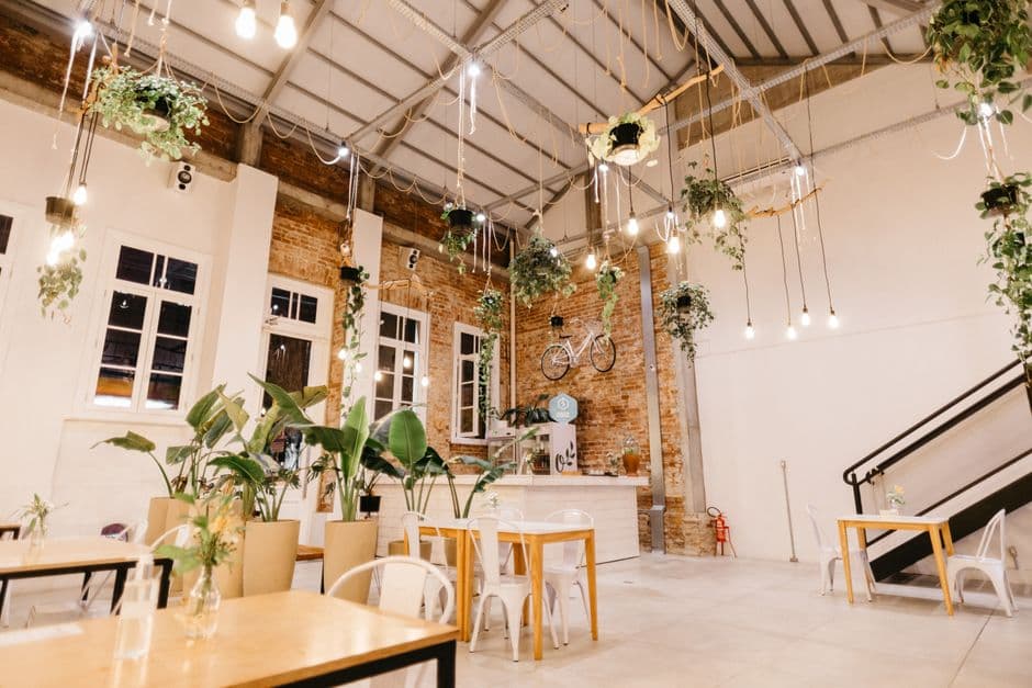 Amazing view of creative interior of restaurant decorated with gold garland and green potted flowers on floor