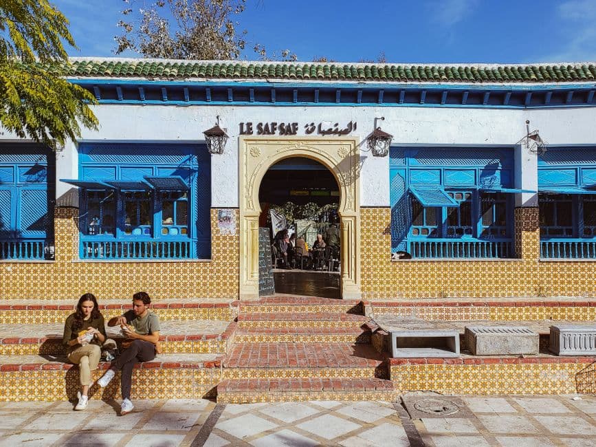 Visitors relaxing at Le Saf Saf, a colorful cafe in Tunis, Tunisia. Bright and inviting atmosphere.