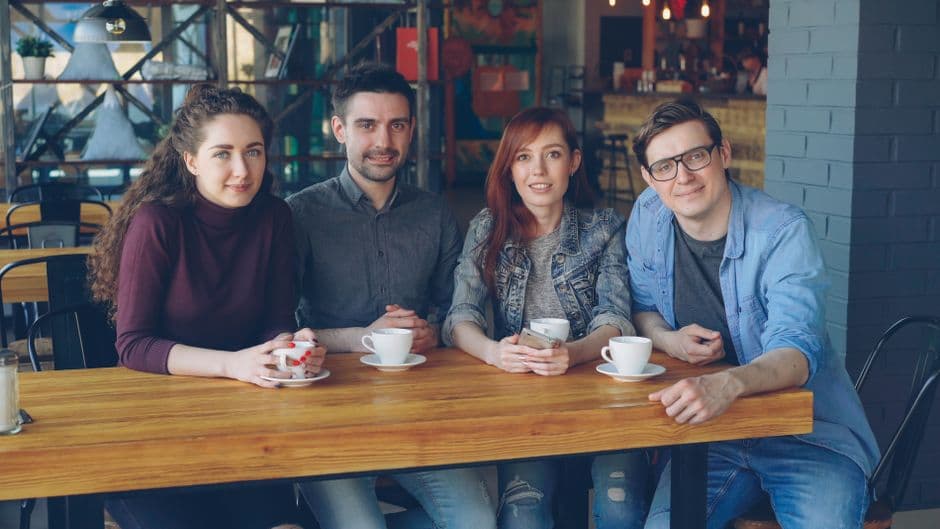 Group of young adults enjoying coffee together at a cozy cafe setting.