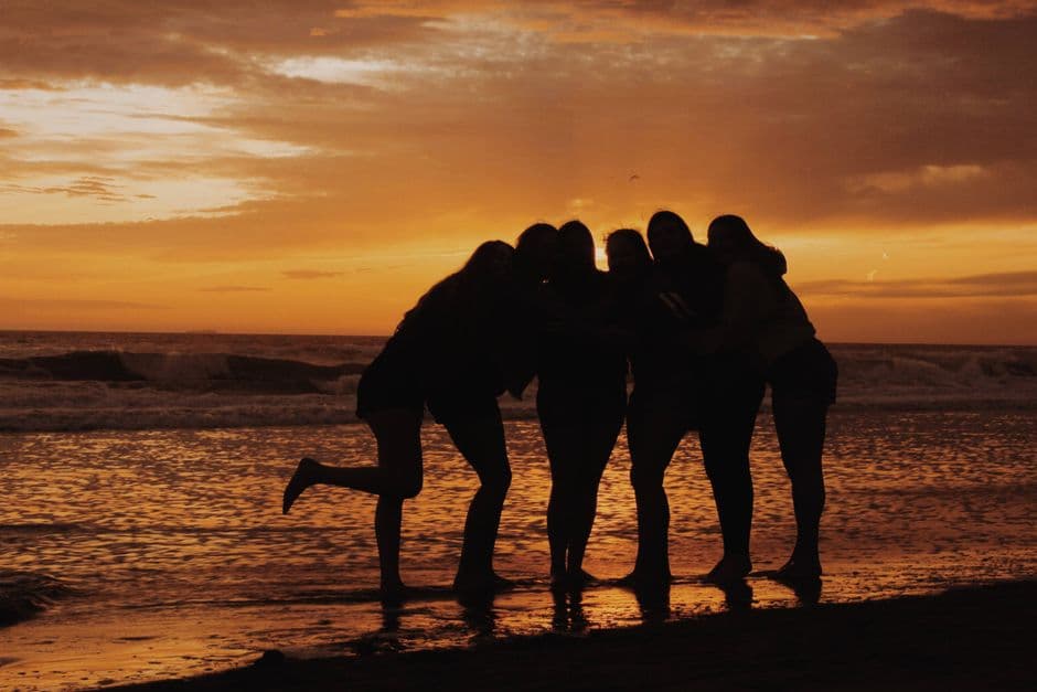 Group of friends silhouetted against a vibrant sunset at Huntington Beach, California.