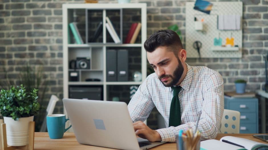 A focused male professional working on a laptop in a stylish modern office.